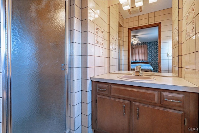 ensuite bathroom featuring a shower stall, ensuite bathroom, tile walls, and vanity