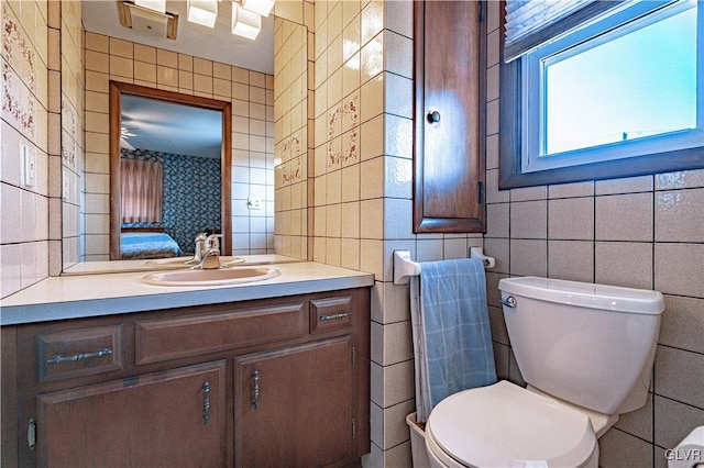 half bathroom with tile walls, toilet, and vanity