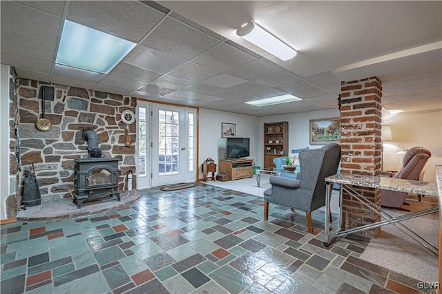 living room with a paneled ceiling and a wood stove