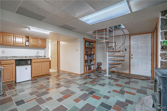 kitchen with light countertops, a paneled ceiling, baseboards, and a sink