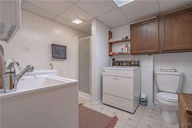 bathroom featuring a drop ceiling, toilet, washer / dryer, and a shower stall