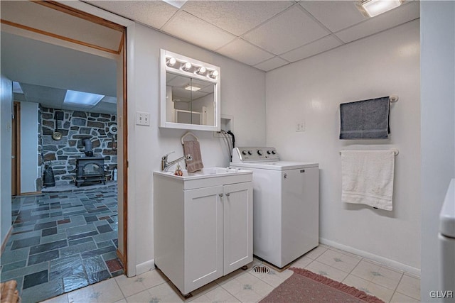 washroom with a sink, baseboards, washer / clothes dryer, and a wood stove