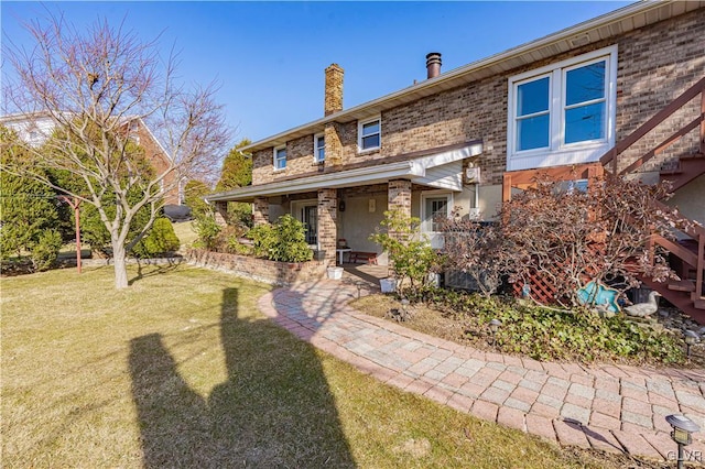 view of front of home featuring a front lawn, brick siding, and a chimney