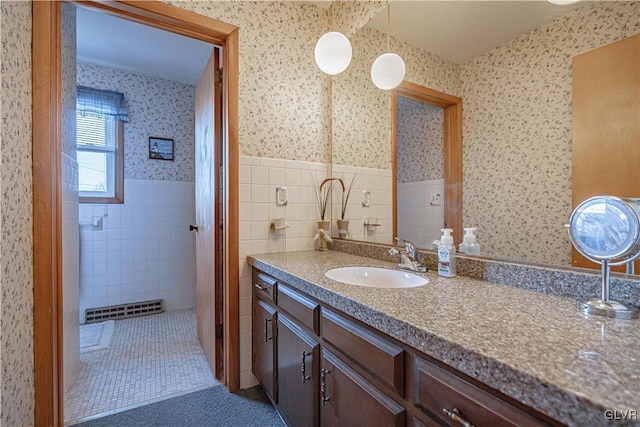 bathroom with tile patterned flooring, wallpapered walls, tile walls, wainscoting, and vanity