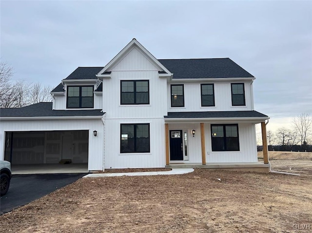 modern farmhouse featuring a porch, a garage, driveway, and a shingled roof