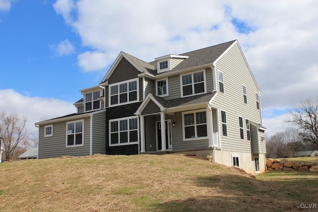 view of front of property featuring a shingled roof and a front lawn