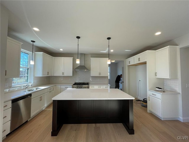 kitchen with dishwasher, light wood-type flooring, stove, wall chimney exhaust hood, and a sink