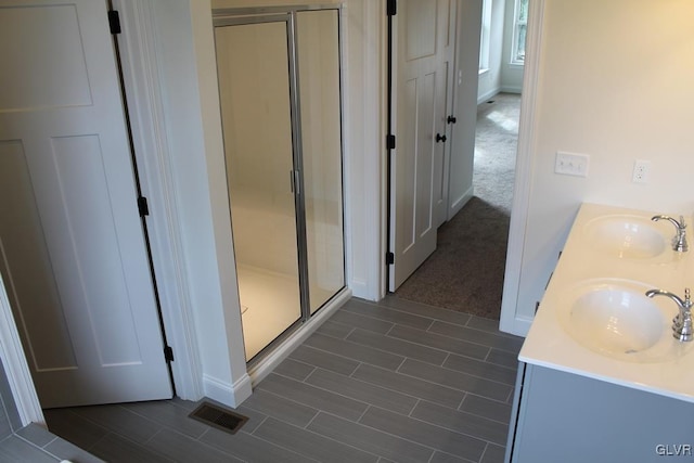 bathroom with double vanity, visible vents, a stall shower, and a sink