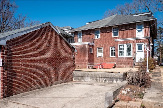 back of property with brick siding and a shingled roof