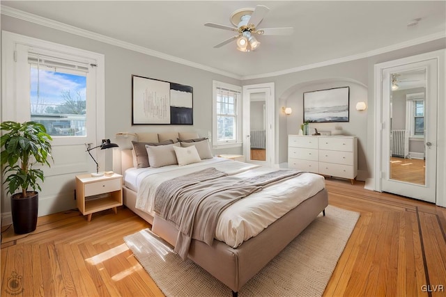 bedroom featuring light wood finished floors, radiator, a ceiling fan, and ornamental molding