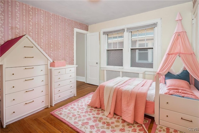 bedroom featuring radiator, wallpapered walls, and wood finished floors