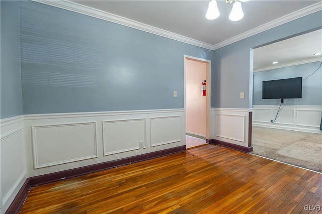 unfurnished room featuring an inviting chandelier, hardwood / wood-style flooring, wainscoting, and ornamental molding