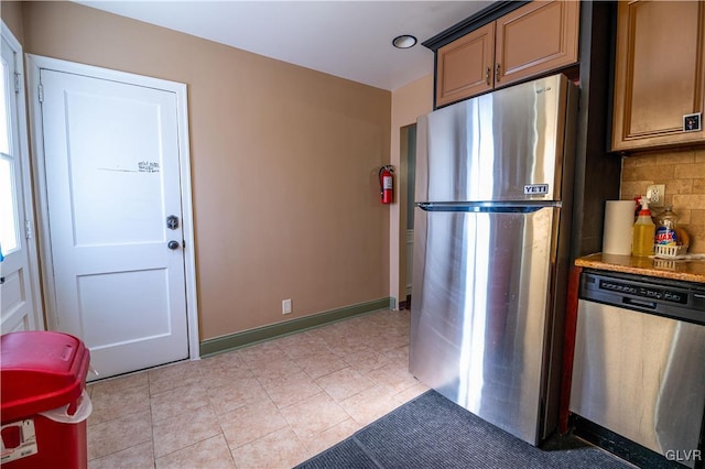 kitchen with decorative backsplash, light tile patterned flooring, baseboards, and appliances with stainless steel finishes