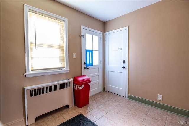 doorway to outside featuring a wealth of natural light, baseboards, radiator, and light tile patterned flooring