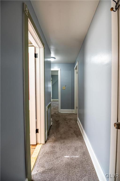 corridor with baseboards and light carpet