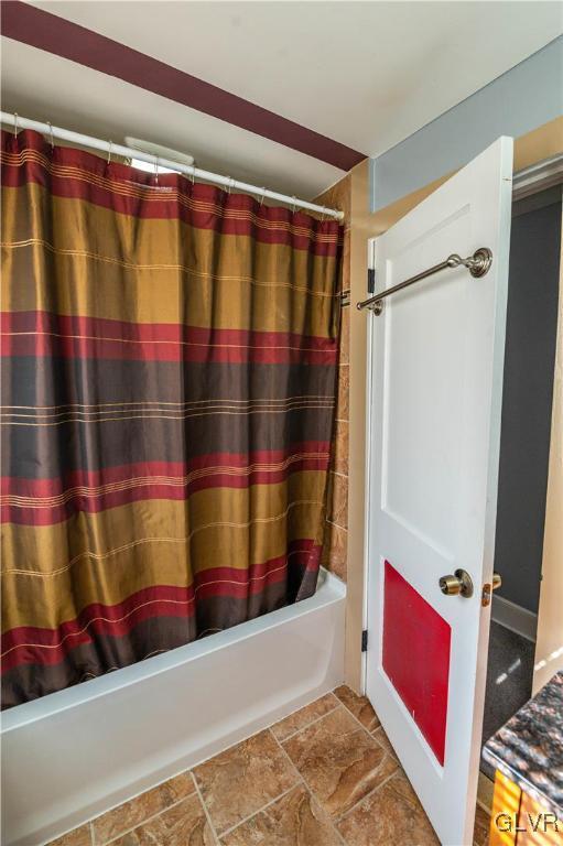 full bathroom featuring stone finish floor and shower / bathtub combination with curtain