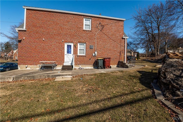 back of property with brick siding and a yard