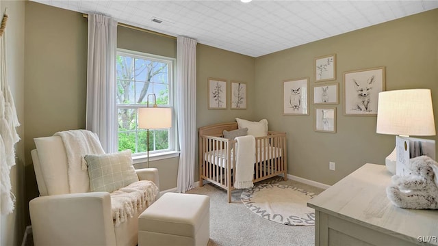 bedroom with baseboards, light carpet, and a crib