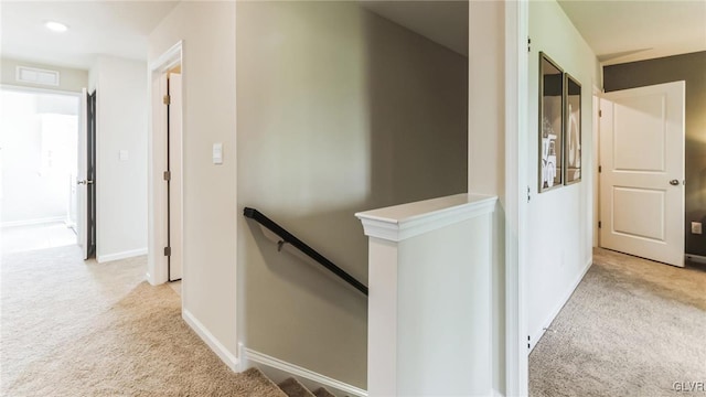 hallway featuring an upstairs landing, baseboards, and light carpet