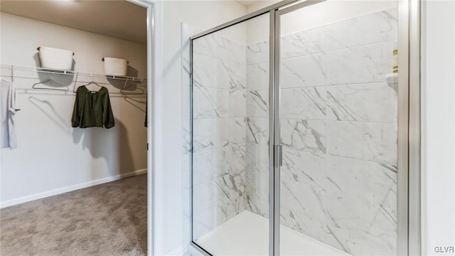 bathroom featuring a walk in closet, baseboards, and a marble finish shower