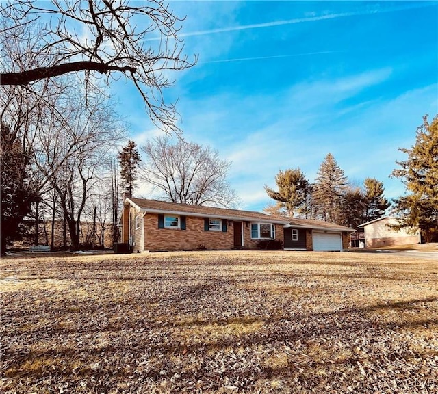 ranch-style home featuring brick siding, a garage, and a chimney