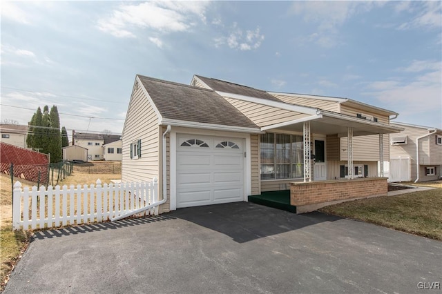 view of front facade with aphalt driveway, fence, roof with shingles, an attached garage, and brick siding