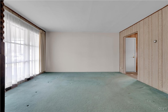 spare room featuring wooden walls, visible vents, and carpet floors