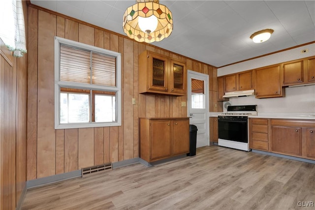 kitchen featuring visible vents, brown cabinets, under cabinet range hood, range with gas stovetop, and a healthy amount of sunlight