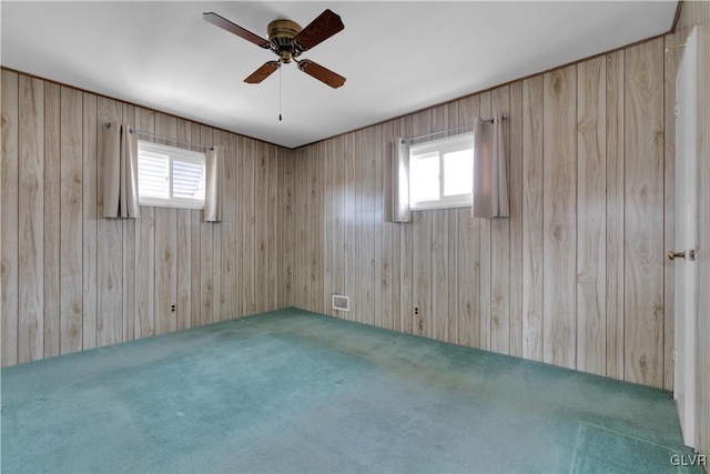 spare room featuring carpet flooring, plenty of natural light, and wood walls