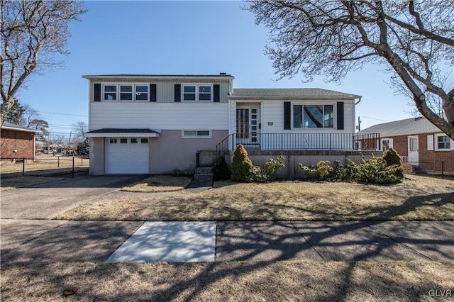 split level home with concrete driveway, fence, and a garage