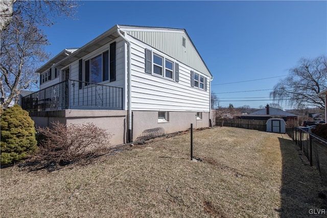 view of property exterior with an outbuilding, a storage shed, a yard, and fence