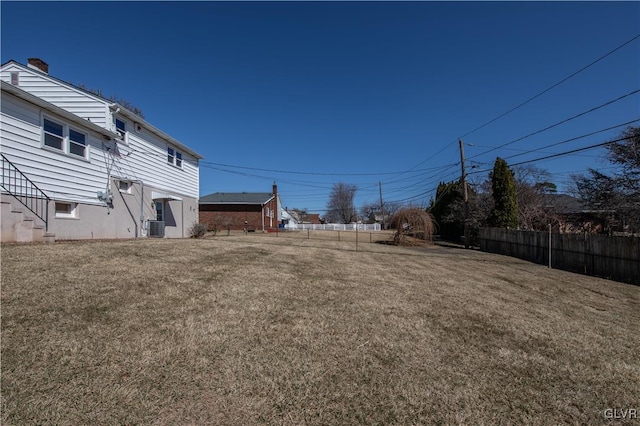 view of yard with central AC unit and fence