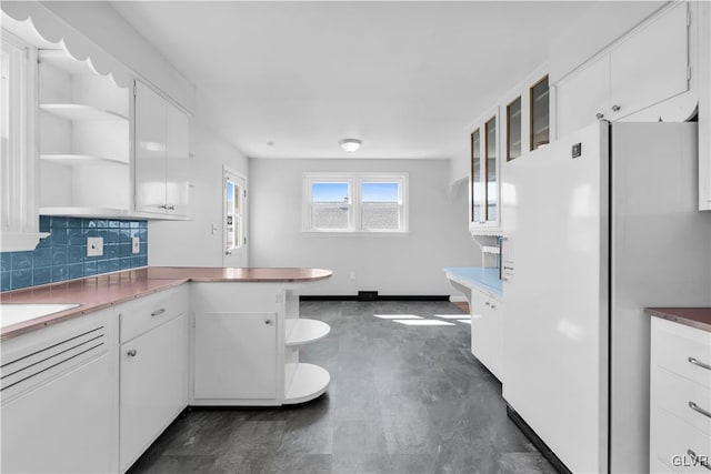 kitchen with open shelves, backsplash, freestanding refrigerator, a peninsula, and white cabinets