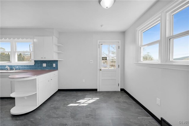 kitchen with open shelves, backsplash, concrete flooring, and white cabinets