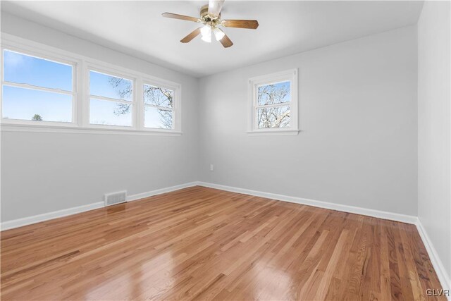 spare room featuring light wood-type flooring, visible vents, baseboards, and ceiling fan