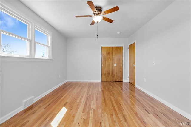 unfurnished room featuring light wood-style flooring, baseboards, visible vents, and ceiling fan