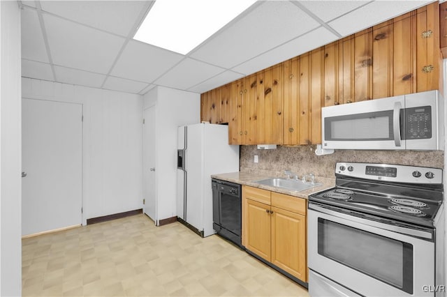 kitchen featuring tasteful backsplash, a drop ceiling, light floors, appliances with stainless steel finishes, and a sink