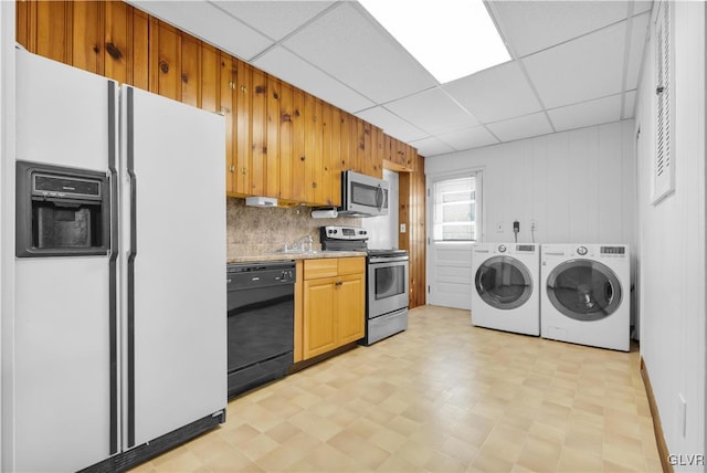 kitchen featuring independent washer and dryer, a drop ceiling, stainless steel appliances, light countertops, and light floors