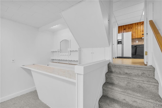 stairway with a drop ceiling, baseboards, and carpet floors