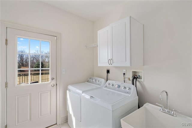 washroom with washing machine and clothes dryer, cabinet space, and a sink