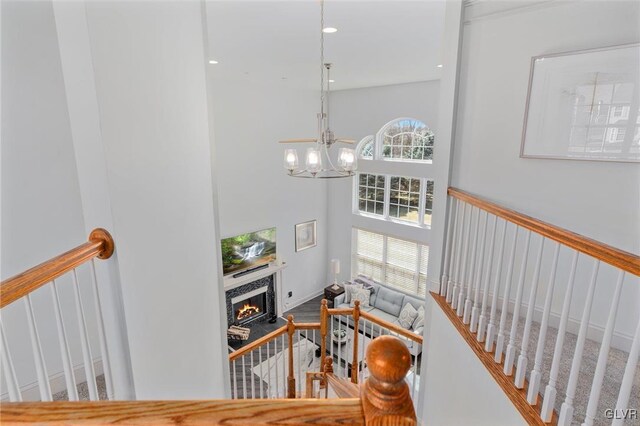 staircase featuring a notable chandelier, a fireplace, and a towering ceiling