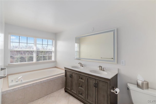 bathroom featuring a bath, double vanity, a sink, tile patterned flooring, and toilet