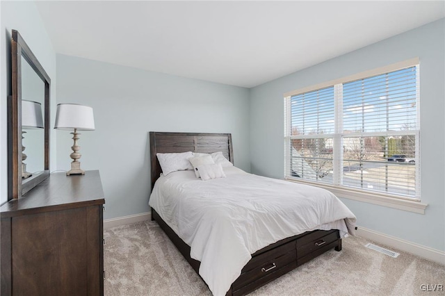 bedroom featuring visible vents, light colored carpet, and baseboards