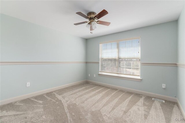 empty room featuring carpet flooring, baseboards, visible vents, and a ceiling fan