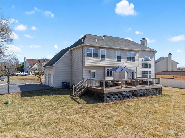 rear view of property with fence, a yard, an attached garage, a chimney, and aphalt driveway