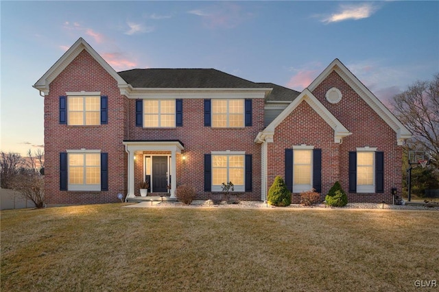 view of front of home with brick siding and a lawn