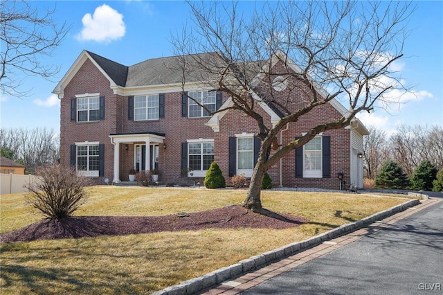 view of front of home featuring brick siding, a front lawn, and fence