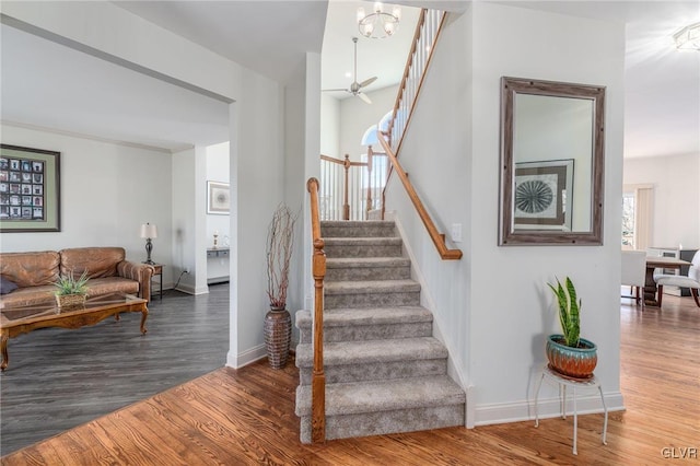 staircase with baseboards, an inviting chandelier, and wood finished floors