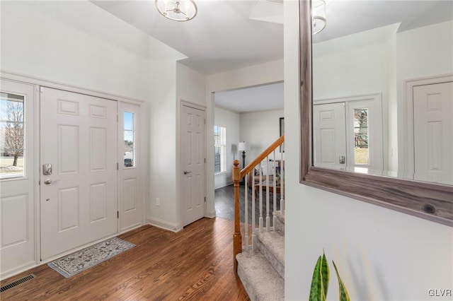 foyer with visible vents, stairway, baseboards, and wood finished floors