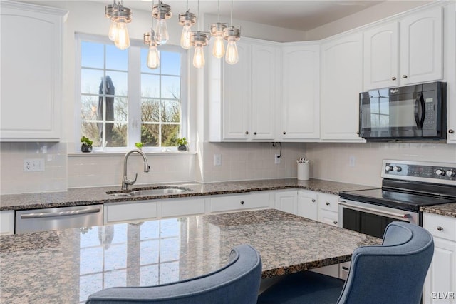 kitchen with backsplash, appliances with stainless steel finishes, a kitchen breakfast bar, white cabinetry, and a sink